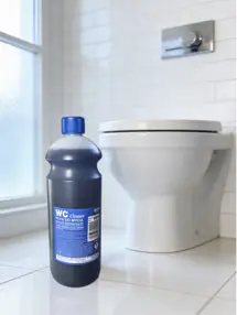 Butelka płynu do WC CLEANER 1L stojąca na podłodze obok muszli klozetowej w łazience.