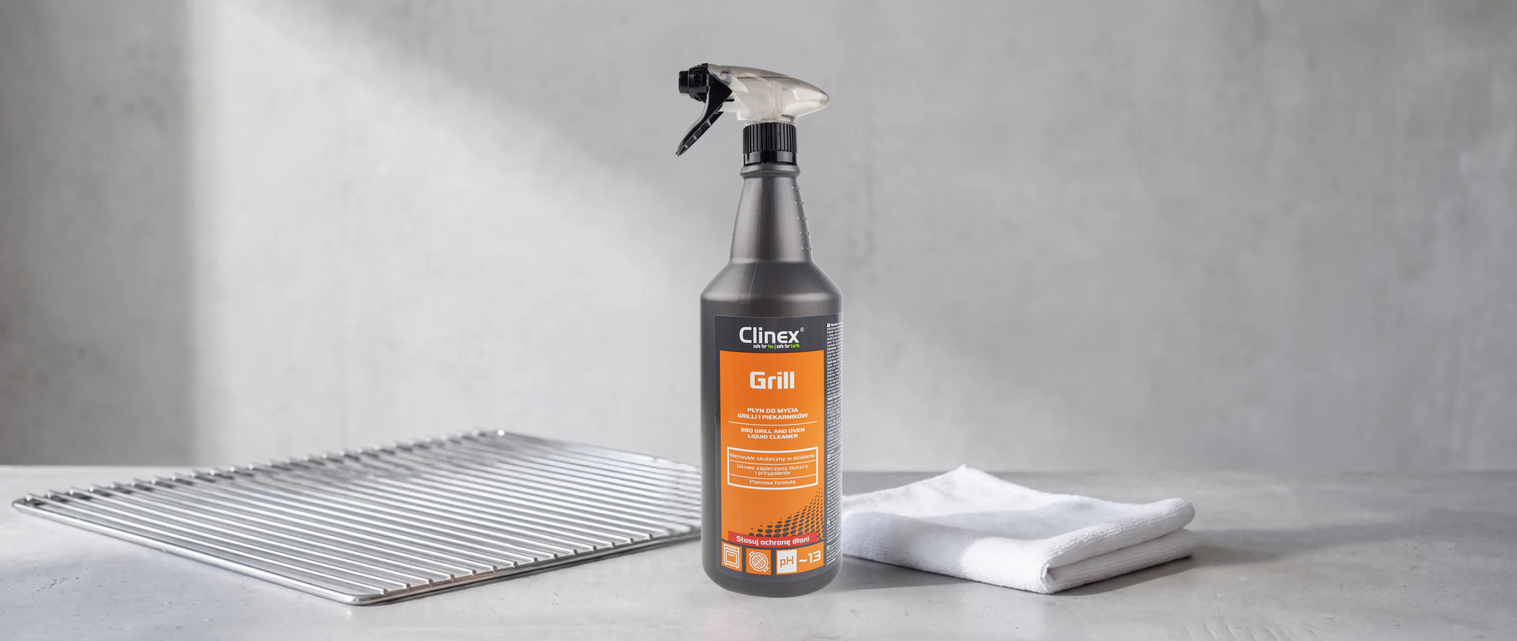 Clinex Grill preparat do czyszczenia grilli spray 1L z atomizerem, obok rusztu i ścierki.